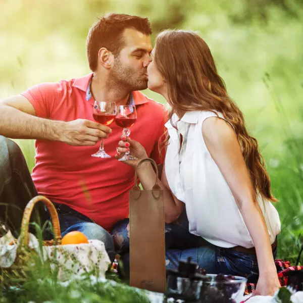 A Couple Kissing While Drinking Wine